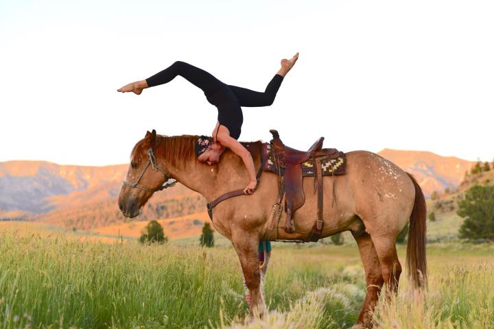 Woman doing yoga pose on a horse